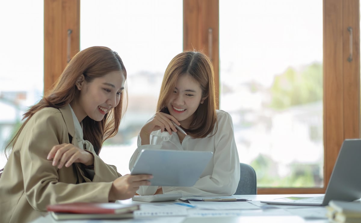 Two beautiful young asian businesswoman working together usi